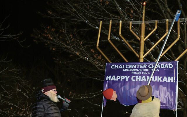 Township committee member Ben Stoller and Short Hills resident Richard Prince helped Rabbi Yehudis Bogomilsky light the 10-foot menorah. (Courtesy Bart Gorin)