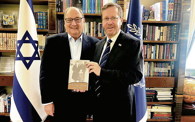 Abe Foxman, left, stands with Israel’s President Isaac Herzog, who  holds a family memoir by Mr. Foxman’s father.
