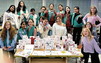 Maddie Rost, founder of Signed With a Smile, at front in off-shoulder sweatshirt, creating cards with a local Girl Scout troop. Maddie Rost, founder of Signed With a Smile, at front in off-shoulder sweatshirt, creating cards with a local Girl Scout troop.