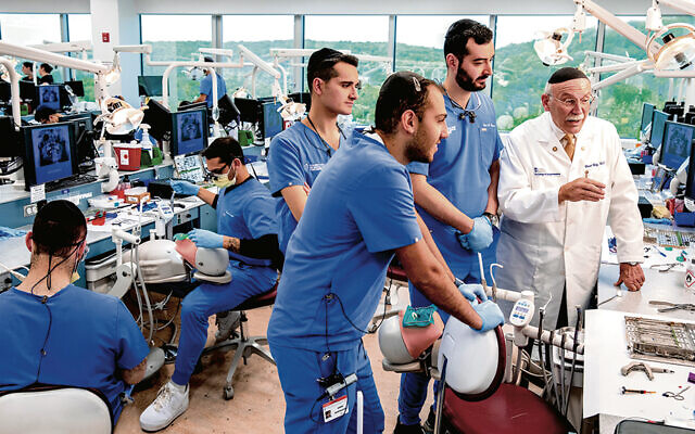 Dr. David Katz looks at a computer with dental students at Touro.
