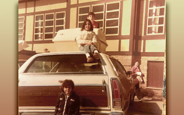 Michele Wolf Bernstein and Jon Wolf are on top of the car, Meredith Wolf Schizer is in front of the car, and our grandma, Beatrice Cohen, is walking in the back.