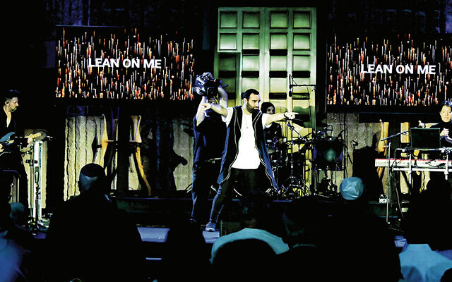 Koolulam’s co-founder and conductor Dor Kaminka, is front and center; he;s backed, from left, by Andrew Weir on guitar, Mike Begigno on drums, and musical director Paul Zhao on keyboards. (Photo by Jerry Siskind) Koolulam’s co-founder and conductor Dor Kaminka, is front and center; he;s backed, from left, by Andrew Weir on guitar, Mike Begigno on drums, and musical director Paul Zhao on keyboards. (Photo by Jerry Siskind)