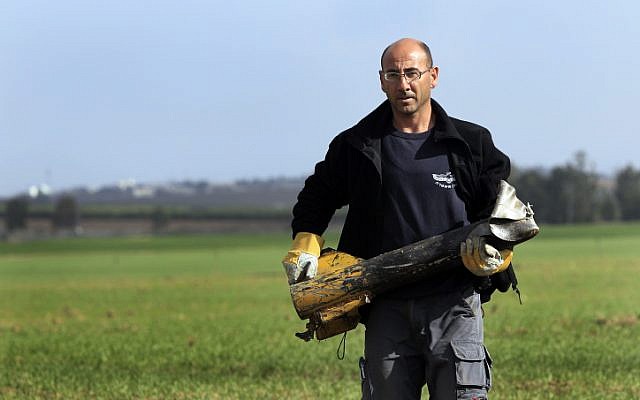 An Israeli police sapper carries a Kassam rocket that landed in an open field near the Israel-Gaza border in December 2011. (Illustrative photo; credit: Tsafrir Abayov/Flash90)