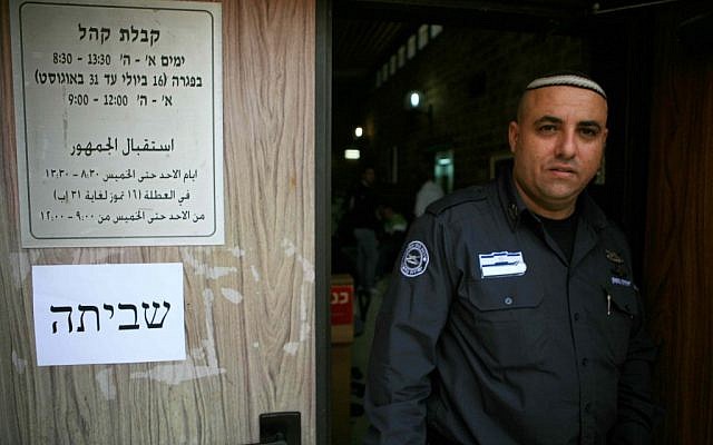 Seorang penjaga keamanan berdiri di luar kantor yang tertutup di Kfar Sava pada hari Kamis.  (kredit foto: Yehoshua Yosef/Flash90)