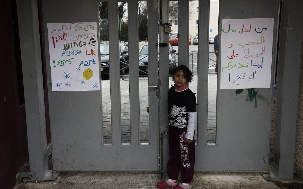 An Arab girl stands near signs against racism at the entrance of the Max Rayne Hand in Hand school for Bilingual education in Jerusalem (photo credit: Kobi Gideon/Flash90)