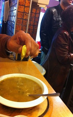 Seorang pelanggan menambahkan sedikit lemon ke dalam sup Marakei dan Felafel Gabai miliknya (kredit foto: Michal Shmulovich, Times of Israel)
