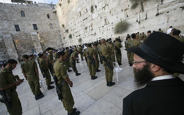 An ultra-Orthodox man looks at Golani soldiers praying at the Western Wall (photo credit: Miriam Alster/Flash90)