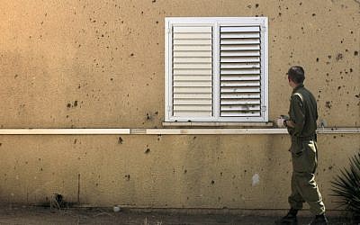 Seorang tentara Israel memeriksa sebuah rumah yang terkena mortir pada hari Sabtu (kredit foto: Tsafrir Abayov/Flash90)