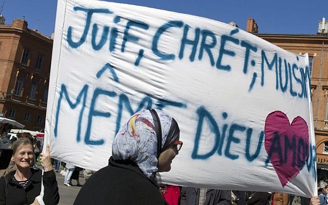 Illustrative: Following a lethal shooting last year at a Jewish school in Toulouse, French mourners carry a banner that reads, "Jews, Christians, Muslims: Same God, Love." (Thibault Camus/AP)