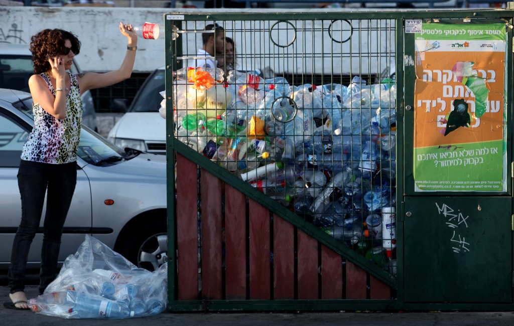 A woman throws a bottle into the recycling bin in central Jerusalem. (photo credit: Nati Shohat/Flash90)