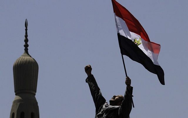 An Egyptian protester chants slogans and waves a national flag in front of a minaret at Tahrir Square, in Cairo, Egypt, Friday. Tens of thousands of protesters packed the square in the biggest demonstration in months against the ruling military. (photo credit: Amr Nabil/AP)