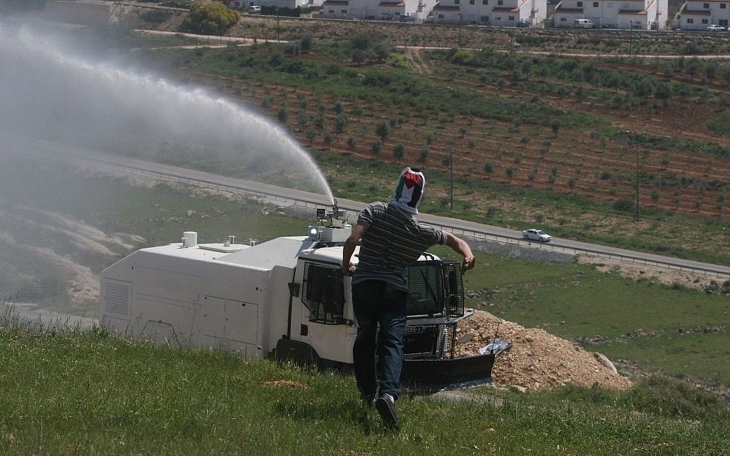 A protester and a water cannon at Nebi Salah in early April (photo credit: Issam Rimawi/Flash 90)