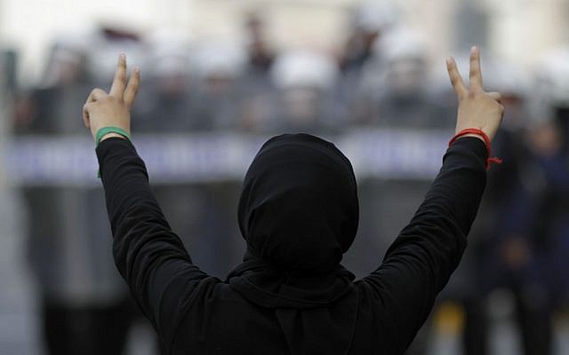 A Bahraini anti-government demonstrator gestures toward riot police during March protests in Manama (photo credit: Hasan Jamali/AP)