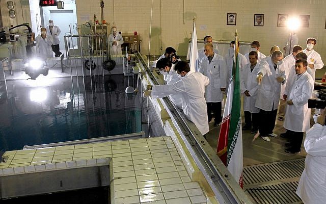 In this Feb. 15, 2012 file photo, provided by the Iranian President's Office, Iranian President Mahmoud Ahmadinejad, right, is escorted by technicians during a tour of Tehran's research reactor center in northern Tehran, Iran. (photo credit: AP/Iranian President's Office, File)