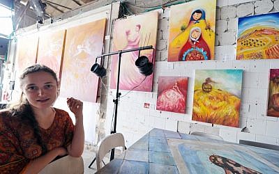 Dina Argov dengan beberapa lukisannya dipamerkan di Kontainer sebagai latar belakang (kredit foto: David Katz)