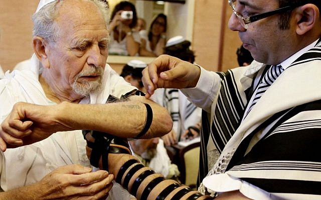 A Holocaust survivor wraps tefillin as he celebrates his bar mitzvah (photo credit: Flash90)