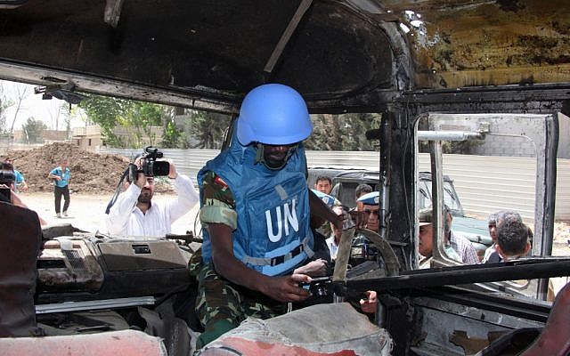 A UN observer photographs a military bus damaged by a roadside bomb near Damascus on Wednesday (photo credit: AP/Bassem Tellawi)