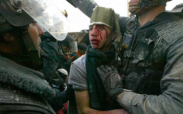 An injured settler is arrested by border policemen during clashes in the West Bank outpost of Amona on January 1, 2006. (photo credit: Olivier Fitoussi/Flash90)