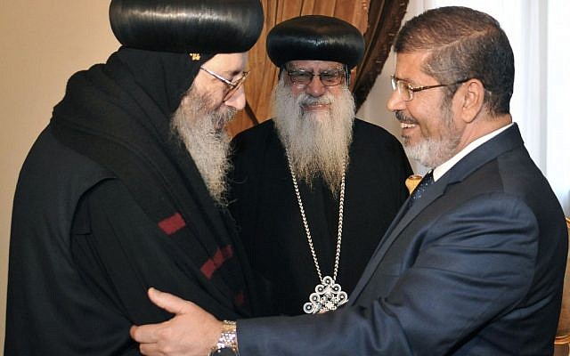 Egyptian President Mohammed Morsi shakes hands with a representative from the Coptic community, in Cairo, June 2012 (photo credit: Middle East News Agency/AP)