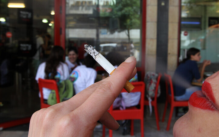 A woman smokes a cigarette outside a cafe. Israel took another step towards becoming smoke-free when strict regulations came into effect that limit smoking in public places. (photo credit: Nati Shohat/Flash90)