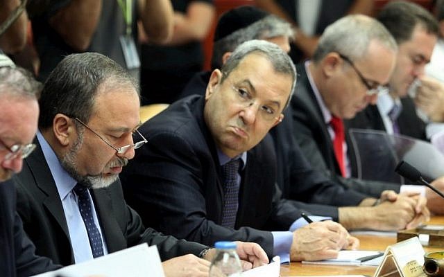 Then-defense minister Ehud Barak (holding pen) looks at then-foreign minister Avigdor Liberman (to his right) at a cabinet meeting led by then-premier Benjamin Netanyahu in 2010. (Amit Shabi/Pool/Flash90)