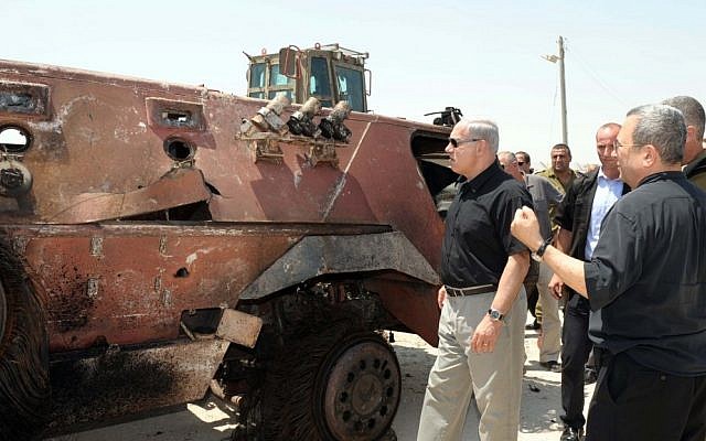 Prime Minister Benjamin Netanyahu, next to a burned out APC, and Defense Minister Ehud Barak, far right, at Kerem Shalom in the wake of the August 5 terror attack that left 16 Egyptian soldiers dead. (photo credit: Avi Ohayon/GPO/Flash90)