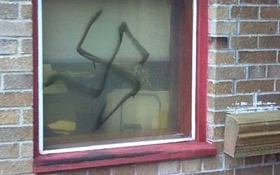 An illustrative photo of a spray-painted swastika on a window (ADL/JTA)