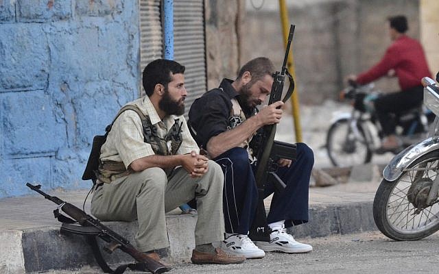 Free Syrian Army soldiers sit on a sidewalk at the northern town of Sarmada, August 1, 2012 (photo credit: AP)