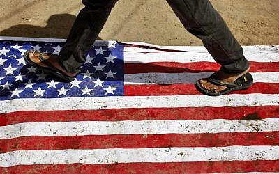 An Indian man walks on an American flag in Hyderabad, India, during a protest against an anti-Islam movie called "Innocence of Muslims," which mocked Islam's Prophet Muhammad Friday, Sept. 14, 2012. (AP Photo/Mahesh Kumar A.)