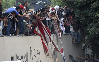 Protesters destroy an American flag at the US Embassy in Cairo and replace it with a black Islamic flag. They climbed the walls and were protesting a film they deemed offensive to Islam. (photo credit: Mohammed Abu Zaid, AP Photo)