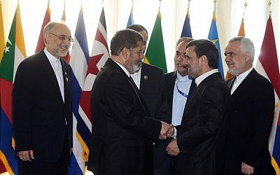 Mohammed Morsi (left) shakes hands with Mahmoud Ahmadinejad at the NAM conference, August 30 (photo credit: AP)