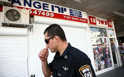 A police officer stands outside a money exchange kiosk in Herzliya whose operators were arrested under suspicion of money laundering on Wednesday, October 10, 2012 (Yehoshua Yosef/Flash90)