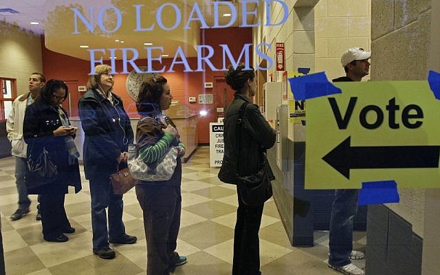 Behind a sign barring loaded firearms in the building, people stand in line to cast their votes on Election Day at a precinct at the Wake County Firearms Education and Training Center in Apex, N.C.,  Nov. 6, 2012. (AP Photo/Gerry Broome)