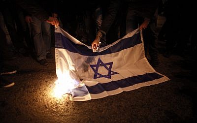 Protesters burn an Israeli flag during a protest against Israel's attacks of the Gaza Strip, in front of the Israeli embassy in Athens Saturday, Nov. 17 (AP Photo/Kostas Tsironis)