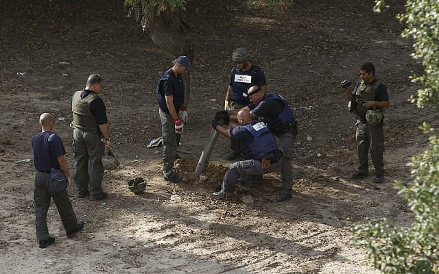 Police sappers remove the remains of a rocket fired by Gazans that landed in Ashkelon in November, 2012. (Photo credit: AP/Tsafrir Abayov)