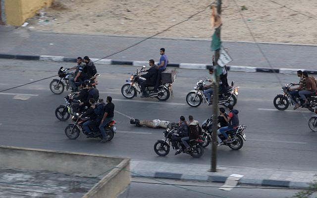 Palestinian gunmen ride motorcycles as they drag the body of a man who was killed as a suspected collaborator with Israel, in Gaza City, November 20, 2012 (photo credit: AP/Hatem Moussa)