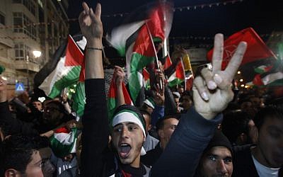 Palestinians celebrate as they watch a screen showing the UN General Assembly votes on a resolution to upgrade the status of the Palestinian Authority to a nonmember observer state, In the West Bank city of Ramallah, Thursday, November 29, 2012. (photo credit: Majdi Mohammed/AP)