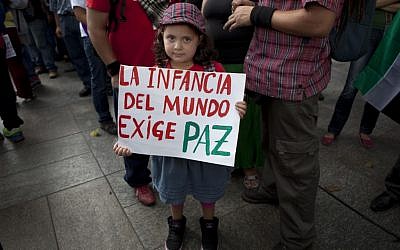 A girl shows her sign that reads in Spanish "The infants of the world demand peace" during a protest against Israel's military operations in Gaza at Bolivar square in Caracas, Venezuela on Wednesday. (photo credit: AP/Ariana Cubillos)