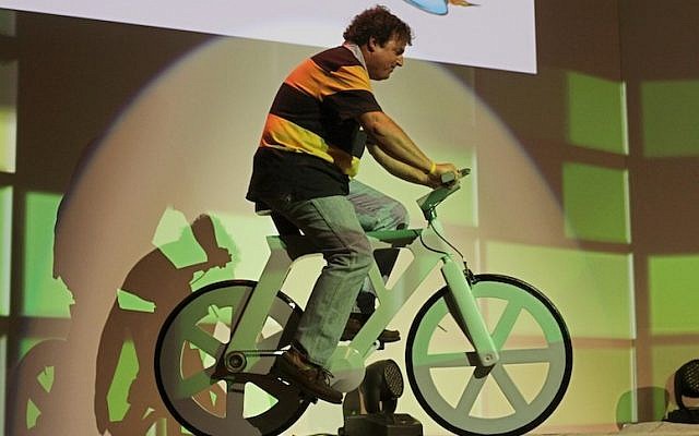 Izhar Gafni rides the cardboard bicycle he developed for the first time in public on stage at Microsoft's ThinkNext event. (Photo credit: Dror Garti/Flash90)