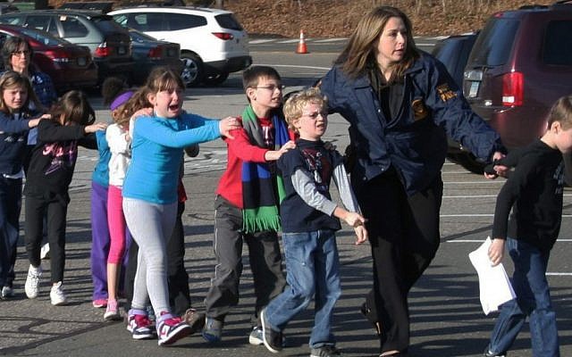 In this photo provided by the Newtown Bee, Connecticut State Police lead a line of children from the Sandy Hook Elementary School in Newtown, Connecticut on December 14, 2012 after a shooting at the school. (AP Photo/Newtown Bee, Shannon Hicks)