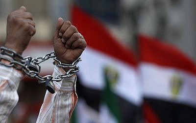 Seorang pengunjuk rasa menunjukkan tangannya dirantai selama demonstrasi di Lapangan Tahrir di Kairo, Mesir, hari Jumat menentang konstitusi yang dirancang oleh kelompok Islam pendukung Presiden Mohammed Morsi (kredit foto: AP/Petr David Josek)