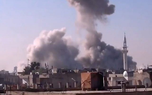 smoke rises from a building in Homs, Syria, after heavy shelling (photo credit: Shaam News Network via AP video)