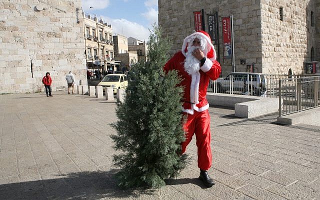 Illustrative photo of a man dressed as Santa Claus with a Christmas tree, outside of Jaffa Gate in the Old City of Jerusalem. (Yossi Zamir/Flash90)