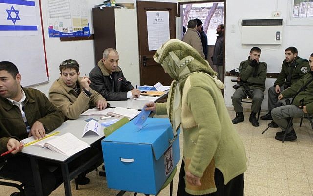 An Arab Israeli woman casts her vote as Israeli border policemen look on at a polling station in the Arab village of Abu Gosh, west of Jerusalem, on February 10, 2009 (photo credit: Nati Shohat/Flash90)
