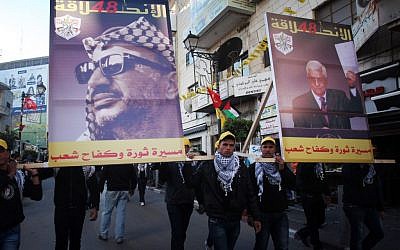 Palestinians marching with posters of Yasser Arafat, left, and Mahmoud Abbas at a Fatah rally in Ramallah in January 2013. (photo credit: Issam Rimawi/Flash90)