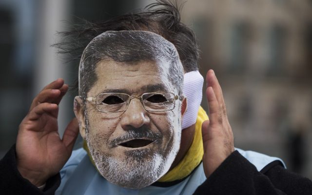 A man covers his face with a mask of Egypt President Mohammed Morsi during a protest in front of the chancellery in Berlin, Germany, Wednesday, Jan. 30, 2013. (photo credit: AP/Markus Schreiber)