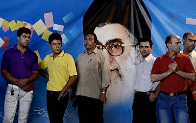 Iranian men line up as they wait to vote for presidential election, while they stand in front of a picture of the supreme leader Ayatollah Ali Khamenei, at a polling station, in downtown in Tehran in 2009. (photo credit: AP/Vahid Salemi)