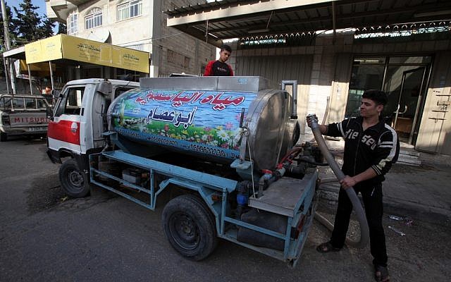 A Palestinian man fills a tank with clean water to be trucked to families who don't have safe drinking water at their homes in Gaza City, in 2010 (photo credit: Wissam Nassar/Flash90)