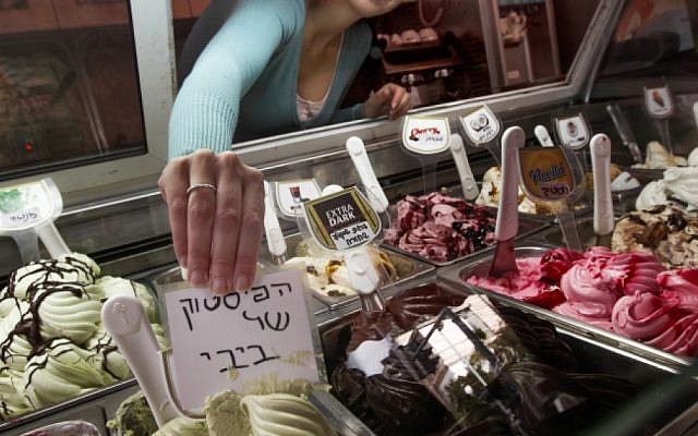 A worker at the Glida Metudela ice cream parlor places a sign reading "Bibi's pistachio" on one of the flavored ice creams, February 2013 (photo credit: Flash90)