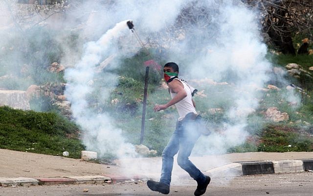 A Palestinian protester uses a slingshot to hurl back a tear gas canister fired by Israeli security forces during clashes next to Ofer prison, near the West Bank city of Ramallah, on February 22, 2013. (photo credit: Issam Rimawi/Flash90)